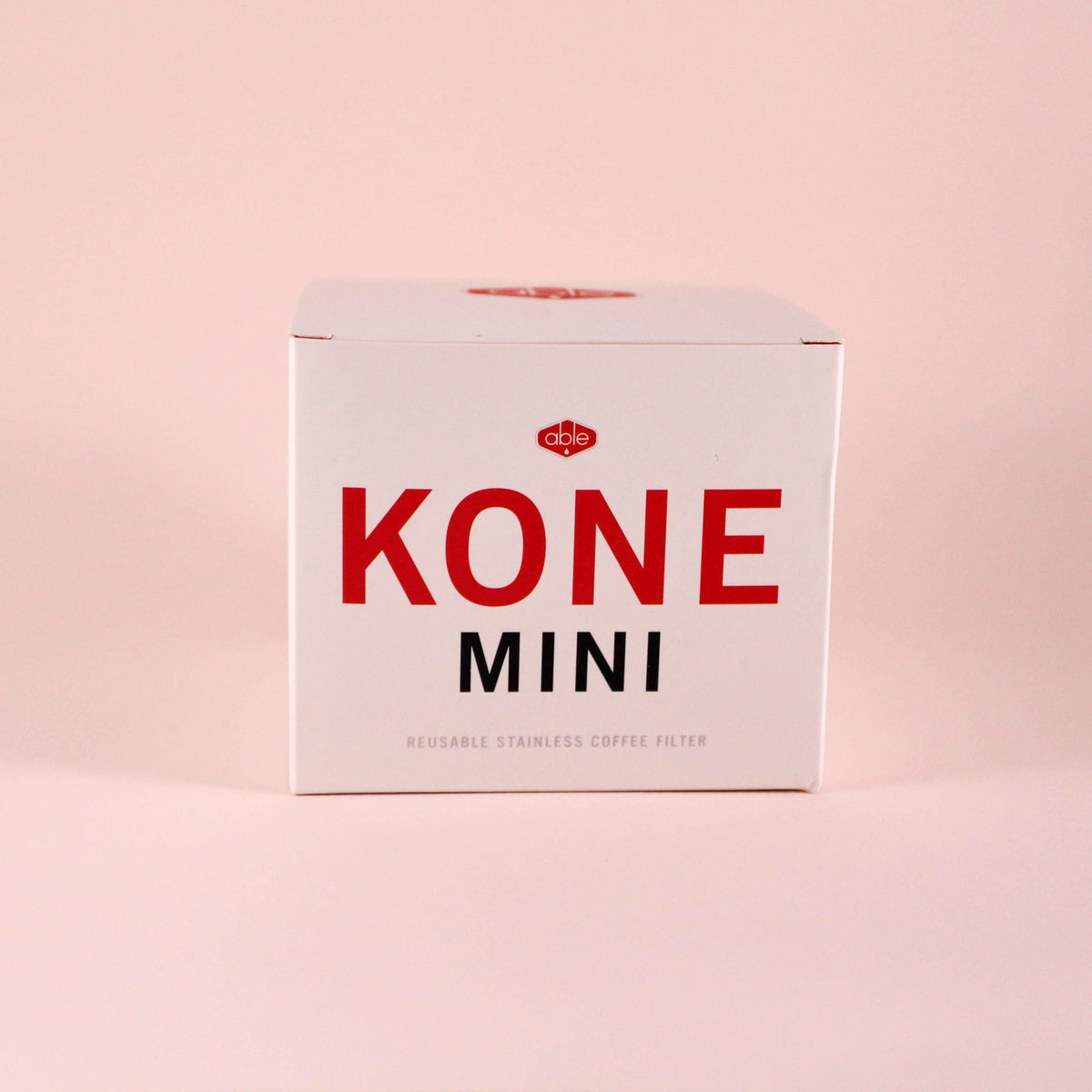 A white box with bold red text reading "Tandem Coffee Roasters Able Coffee Kone Mini" and smaller text stating "reusable stainless steel coffee filter" on a light pink background.
