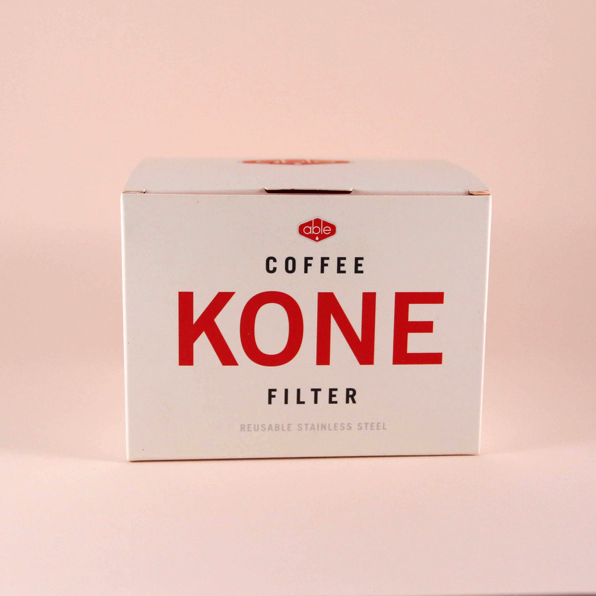A box of reusable stainless steel Able Coffee Kone filter by Tandem Coffee Roasters, labeled "reusable stainless steel," against a pale pink background.
